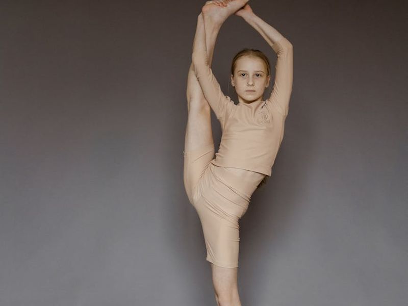 Person performing a deep stretch in a bright studio.